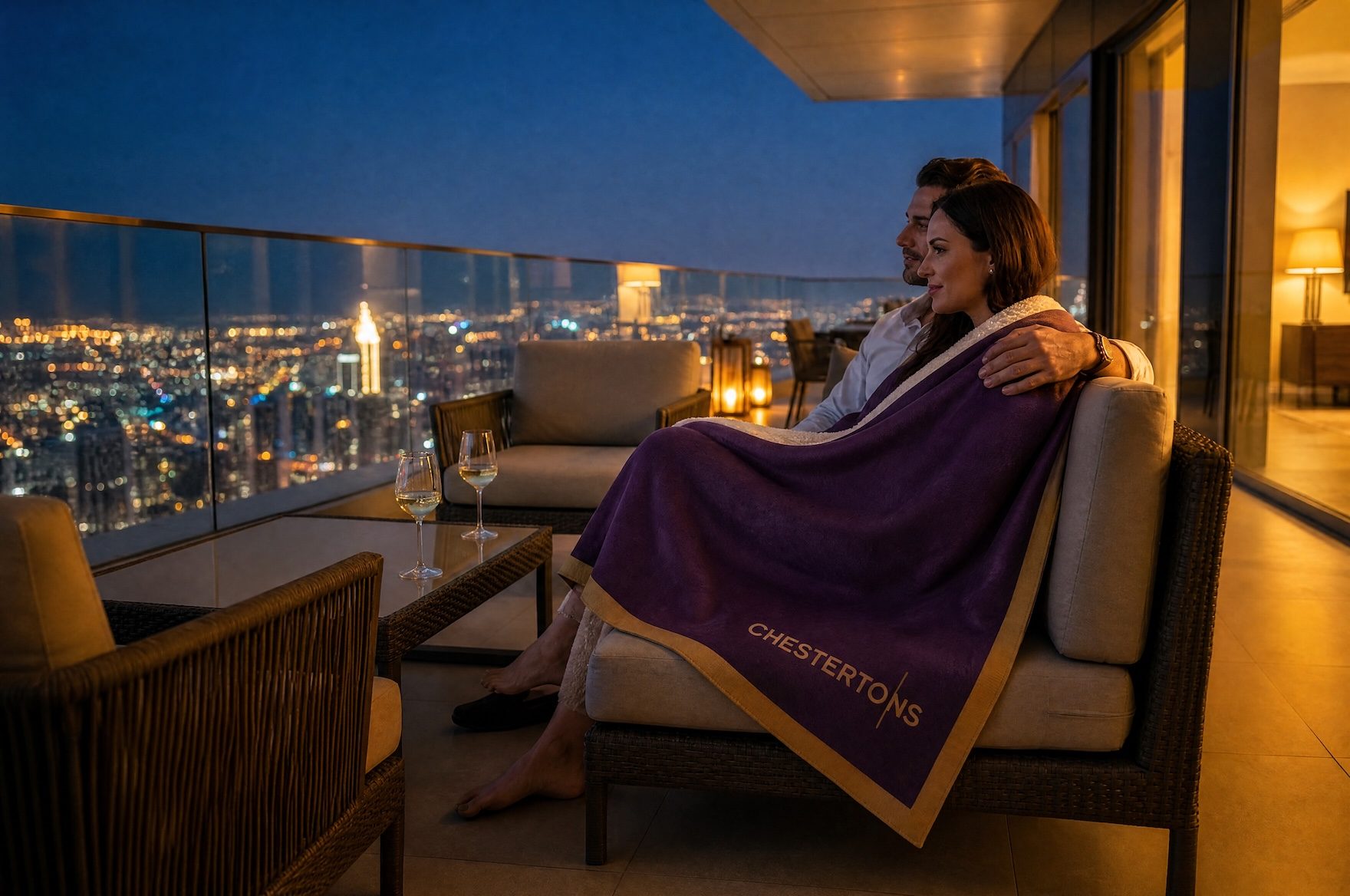 Couple wrapped in the Chestertons blanket on a high-rise terrace at night