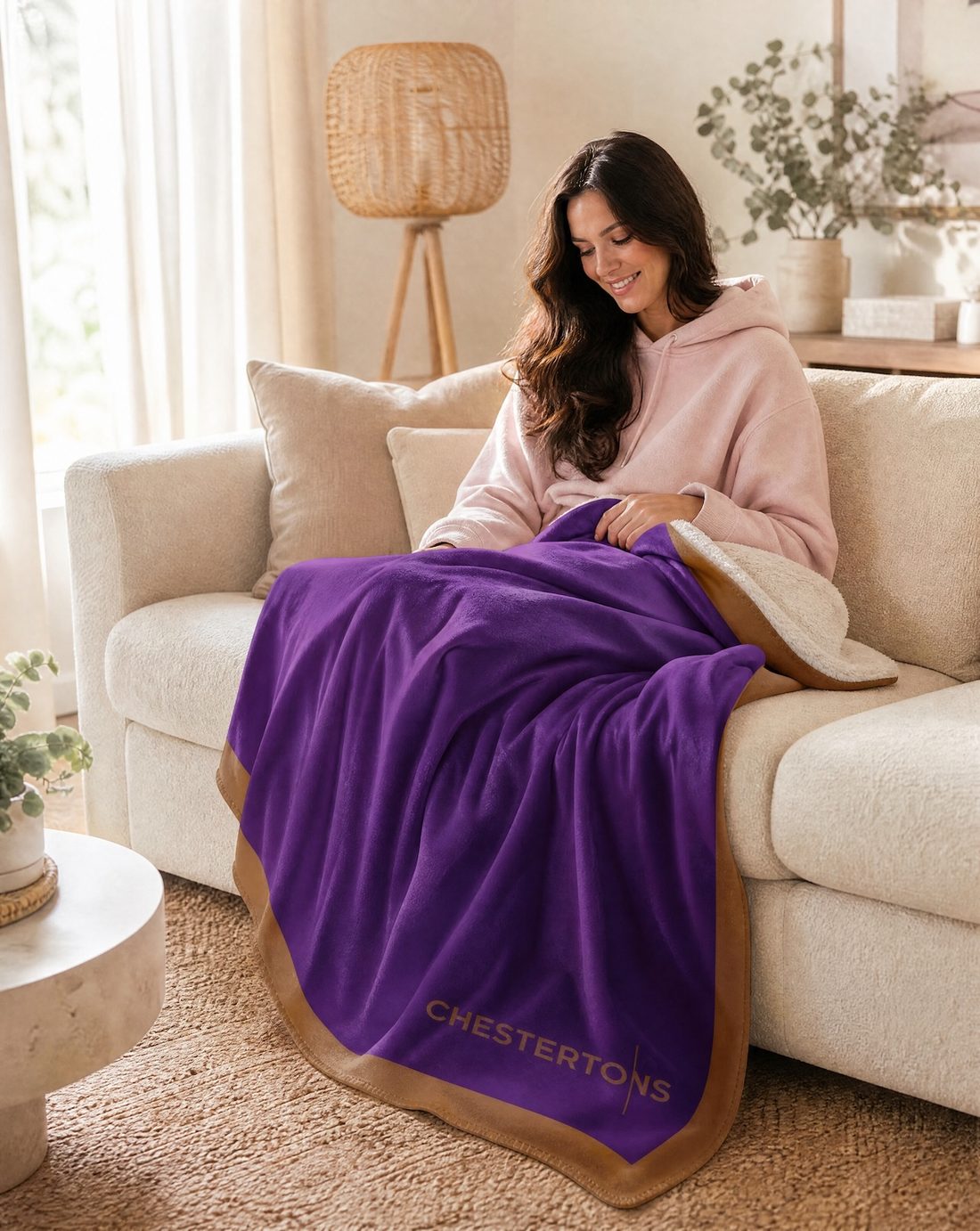Woman on a cream sofa with the blanket across her lap